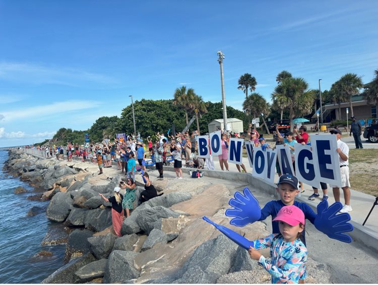 A crowd waves and holds signs reading